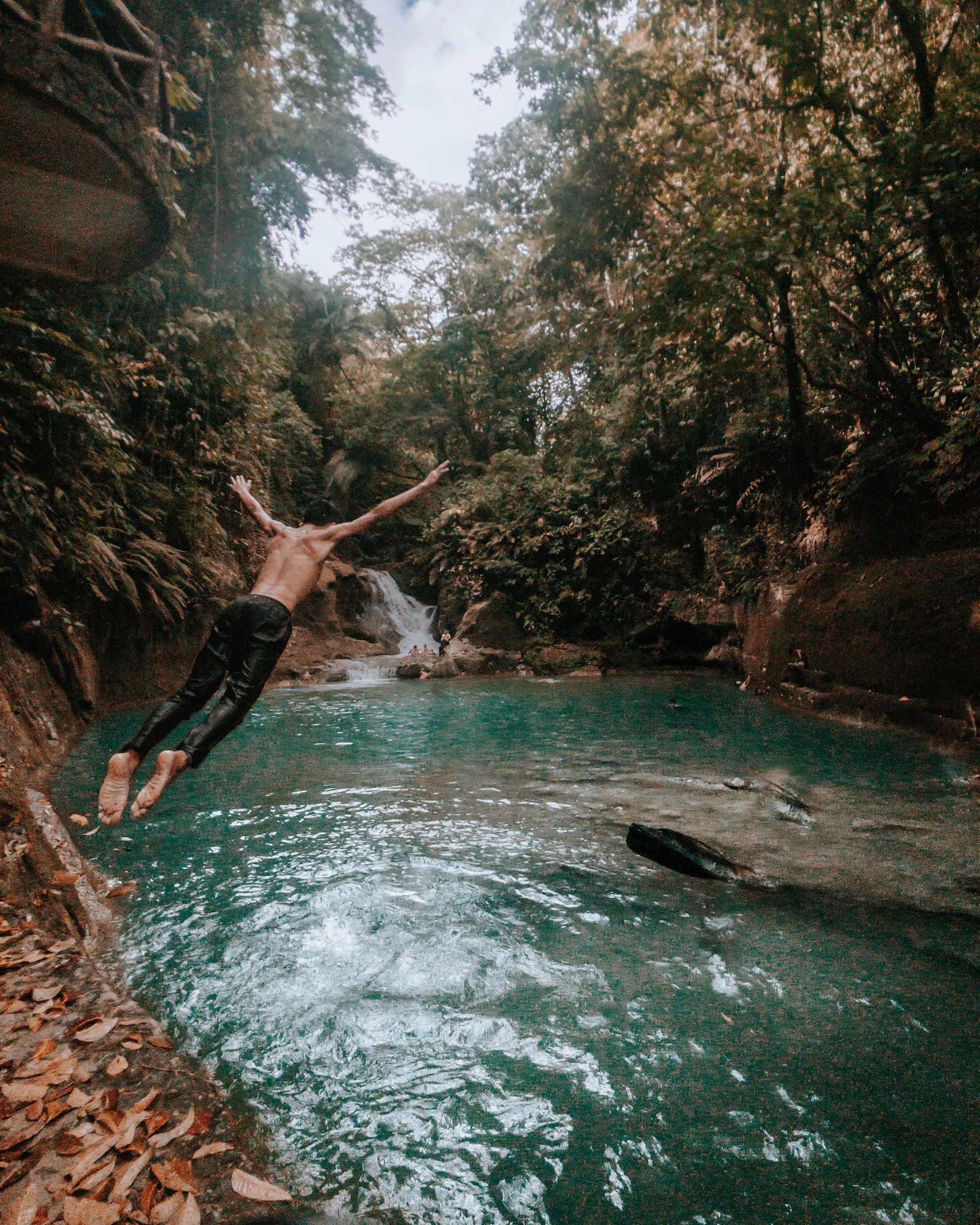 man jumping into waterfall