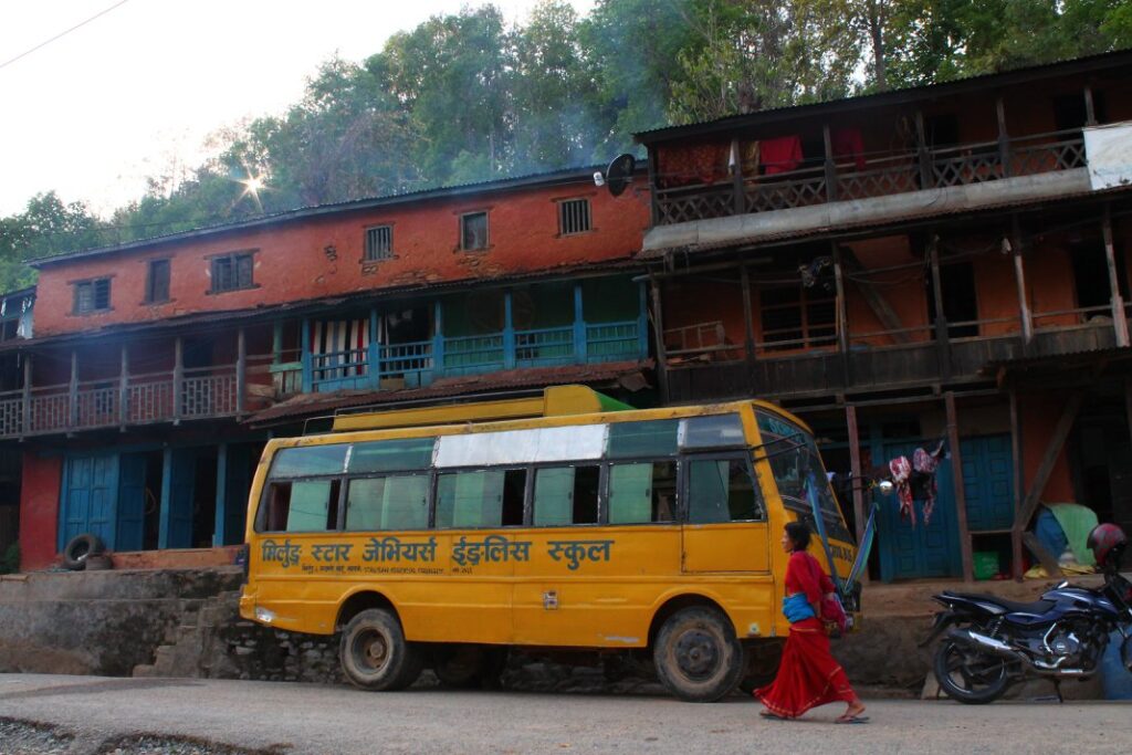 Yellow bus parked in front of houses on street.